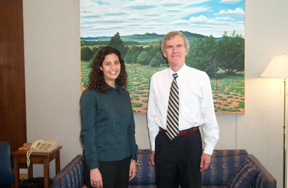 Photo of intern Alexandra Sanchez, who is standing beside Senator Bingaman in the Senator's office. Both are looking forward and smiling.