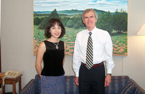 Photo of intern Maria Najera, who is standing beside Senator Bingaman in the Senator's office. Both face forward and are smiling