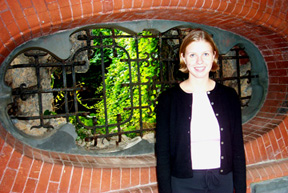 Alison French standing in front of a wrought iron design in a red brick wall