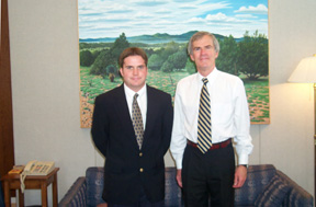 Photo of intern Brandon Winchester, who is standing with Senator Bingaman in the Senator's office. Both are facing forward and smiling.