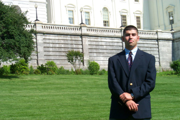 Photo of intern Miguel Suazo, who stands on the well-manicured green lawn of the Capitol building with his hands folded before him.
