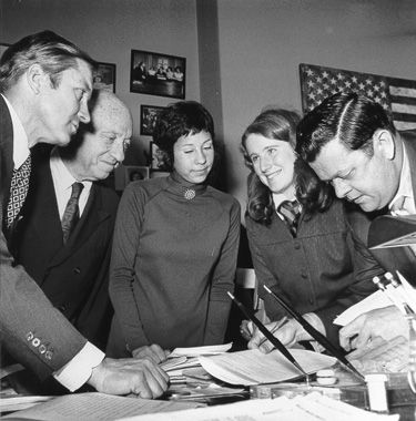 Two female Senate pages with several senators.