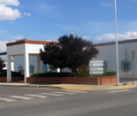 Photo of 200 East Fourth Street, a one-story white building with red trip, landscaped with a tree in the foreground.