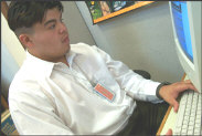 Artistic graphic of an intern sitting at a computer reading what is on the monitor. His intern ID badge hangs from his neck